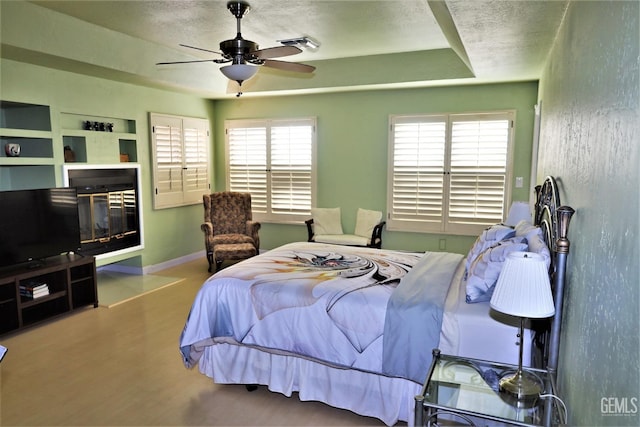 bedroom featuring light wood-type flooring, ceiling fan, and a raised ceiling