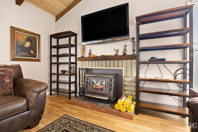 living room with lofted ceiling, wood ceiling, a wood stove, wood finished floors, and baseboards