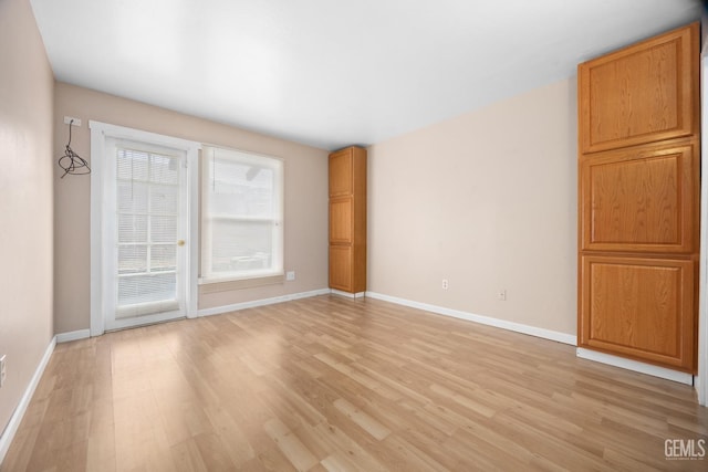 unfurnished room with light wood finished floors and baseboards