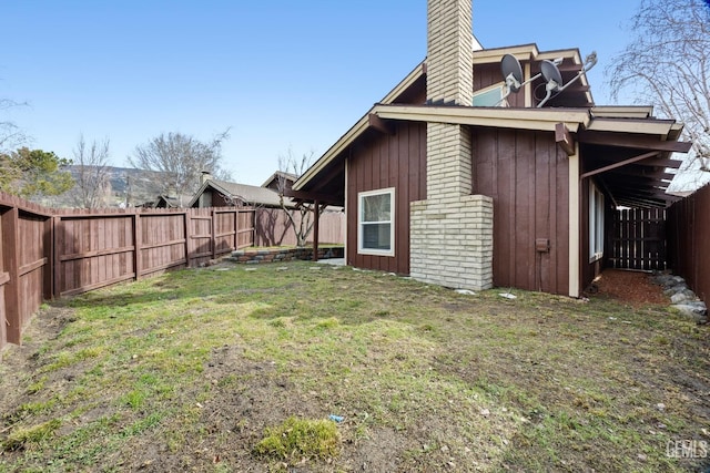 exterior space with a yard, a chimney, and a fenced backyard