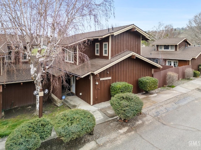 view of front of house featuring roof with shingles and fence