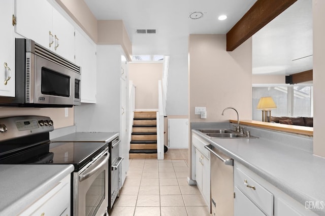 kitchen featuring visible vents, beamed ceiling, stainless steel appliances, a sink, and light tile patterned flooring