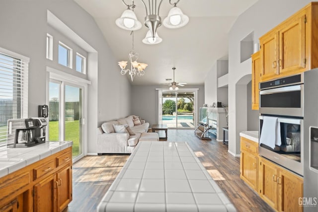 kitchen with decorative light fixtures, dark wood-style floors, open floor plan, double oven, and tile counters