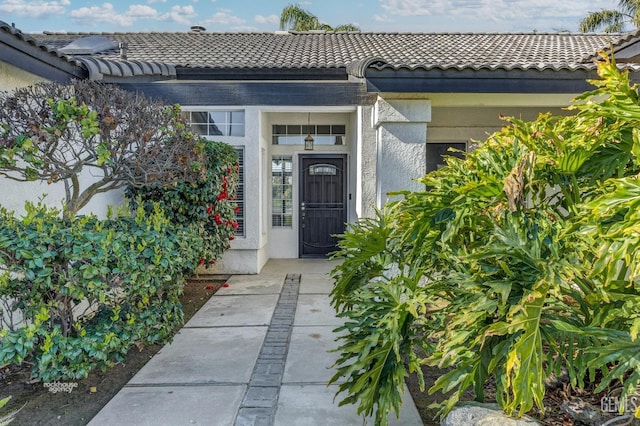 property entrance with a tile roof and stucco siding