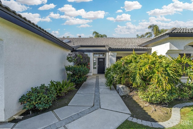 entrance to property featuring a tiled roof and stucco siding