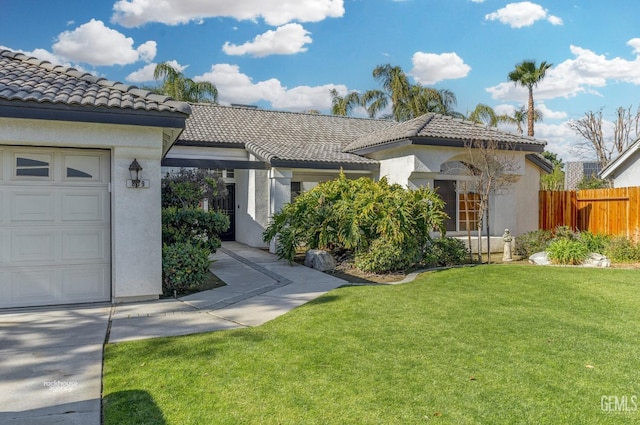 mediterranean / spanish house featuring stucco siding, a tile roof, a front yard, and fence