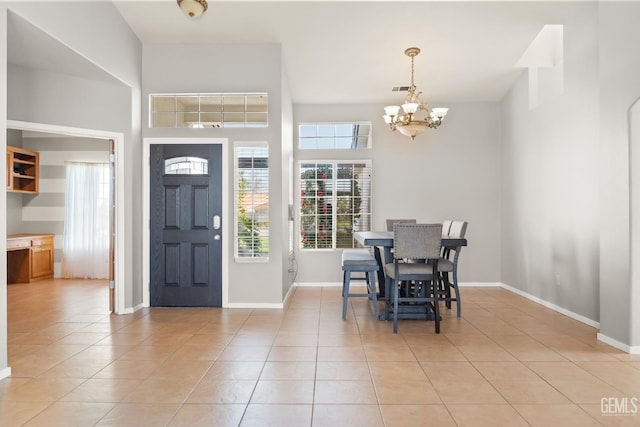 foyer entrance featuring an inviting chandelier, light tile patterned floors, baseboards, and a towering ceiling