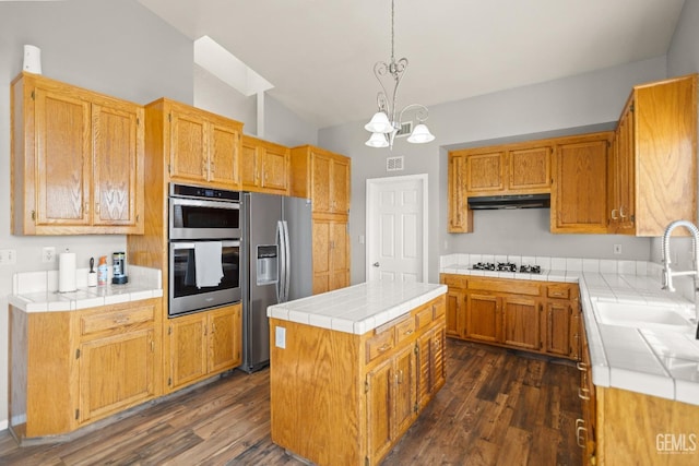 kitchen featuring a kitchen island, under cabinet range hood, dark wood finished floors, appliances with stainless steel finishes, and a sink