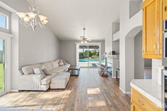 living area featuring baseboards, high vaulted ceiling, dark wood-style floors, and ceiling fan with notable chandelier