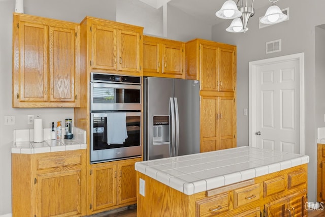 kitchen with visible vents, a notable chandelier, stainless steel appliances, tile counters, and hanging light fixtures