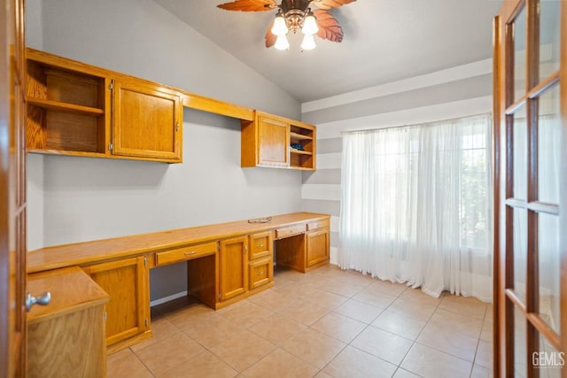 unfurnished office featuring light tile patterned floors, lofted ceiling, a ceiling fan, and built in desk