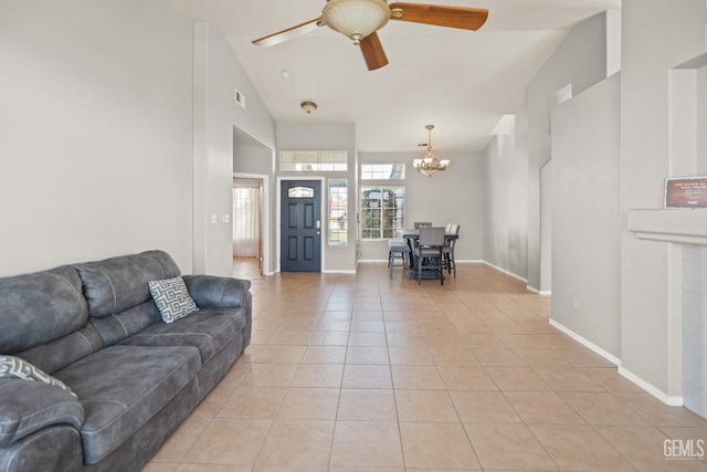 living room with visible vents, high vaulted ceiling, ceiling fan with notable chandelier, light tile patterned floors, and baseboards