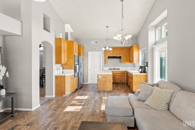 kitchen featuring visible vents, a kitchen island, light countertops, open floor plan, and a chandelier