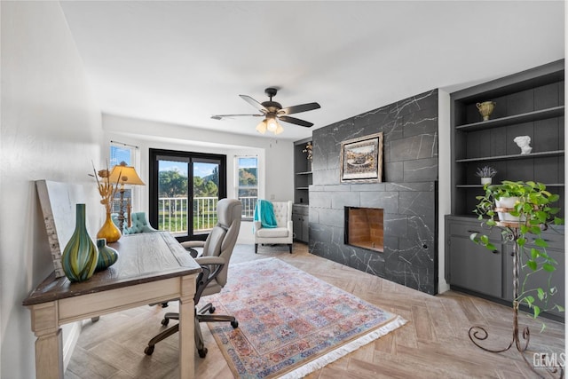 office area with built in features, a ceiling fan, and a premium fireplace