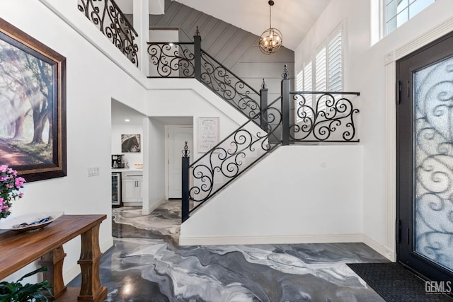 foyer entrance featuring stairs, marble finish floor, wine cooler, and a high ceiling