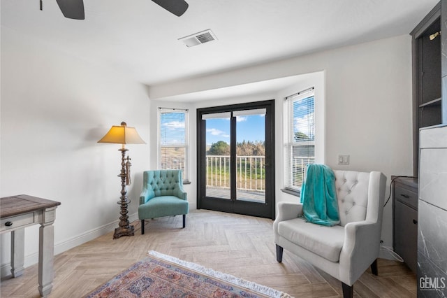 sitting room featuring visible vents, a ceiling fan, baseboards, and a healthy amount of sunlight