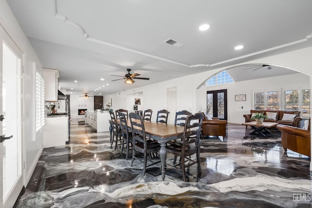 dining area featuring arched walkways, ceiling fan, and marble finish floor