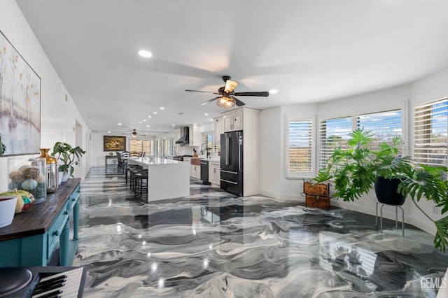living room featuring a ceiling fan, recessed lighting, plenty of natural light, and marble finish floor