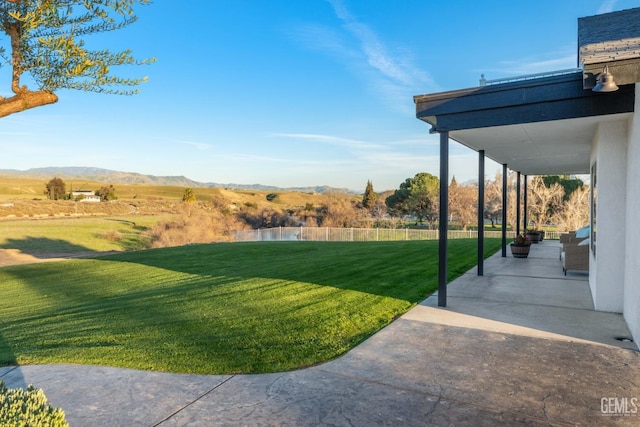 view of yard with a patio, a mountain view, and fence