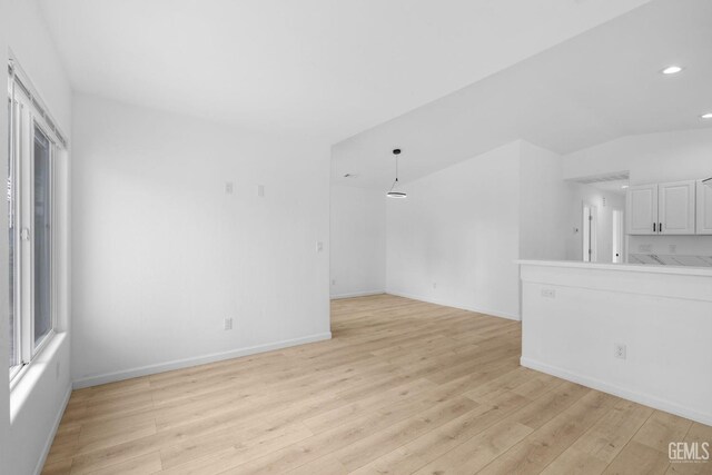 unfurnished living room with plenty of natural light, light wood-type flooring, and vaulted ceiling