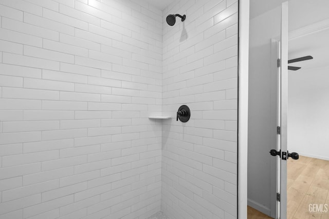 bathroom featuring a tile shower and wood-type flooring