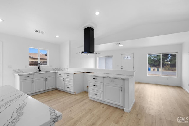 kitchen with sink, ventilation hood, kitchen peninsula, vaulted ceiling, and white cabinets