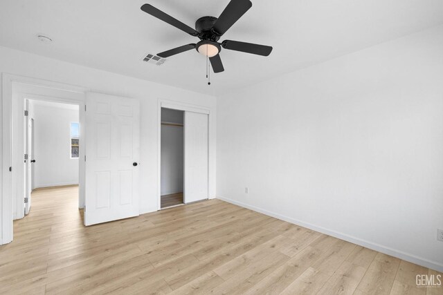 unfurnished bedroom featuring a closet, light hardwood / wood-style flooring, and ceiling fan