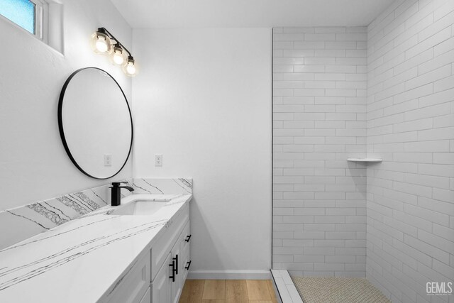 bathroom featuring hardwood / wood-style floors, vanity, and tiled shower