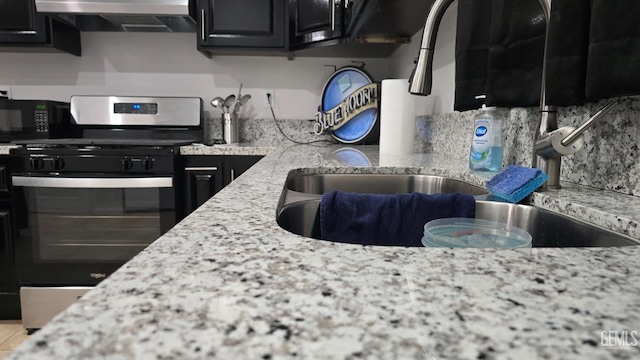 6304 Stanley St, Bakersfield, CA 93308 - kitchen with exhaust hood, light stone counters, dark cabinets, a sink, and stainless steel range with gas stovetop