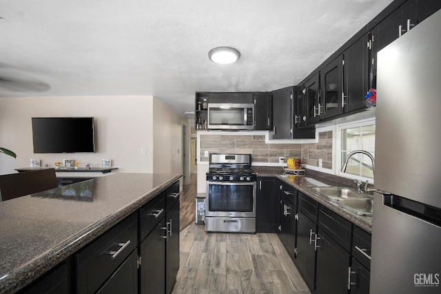 348 Petrol Rd Unit 394, Bakersfield, CA 93308 - kitchen featuring stainless steel appliances, dark cabinetry, light wood-style floors, dark countertops, and a textured ceiling