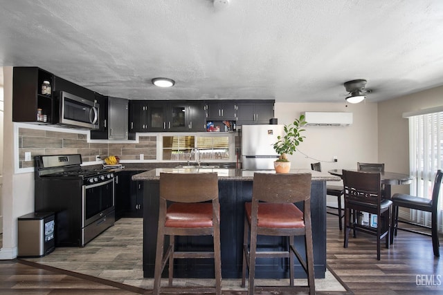 348 Petrol Rd Unit 394, Bakersfield, CA 93308 - kitchen with appliances with stainless steel finishes, dark cabinets, dark wood-style floors, an AC wall unit, and a center island