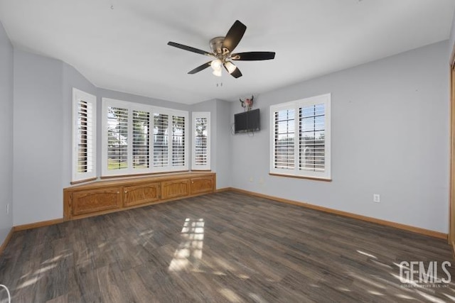 empty room with a ceiling fan, baseboards, and wood finished floors