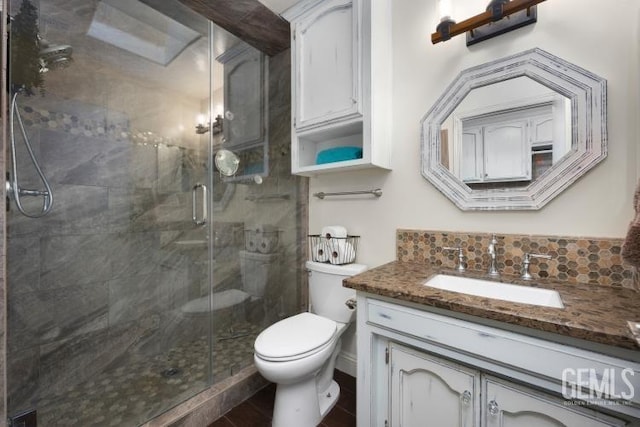 bathroom featuring toilet, a stall shower, and vanity