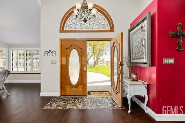 entrance foyer with baseboards, a towering ceiling, wood finished floors, and a wealth of natural light