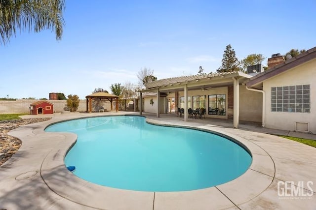 outdoor pool featuring a gazebo, a storage shed, ceiling fan, an outbuilding, and a patio
