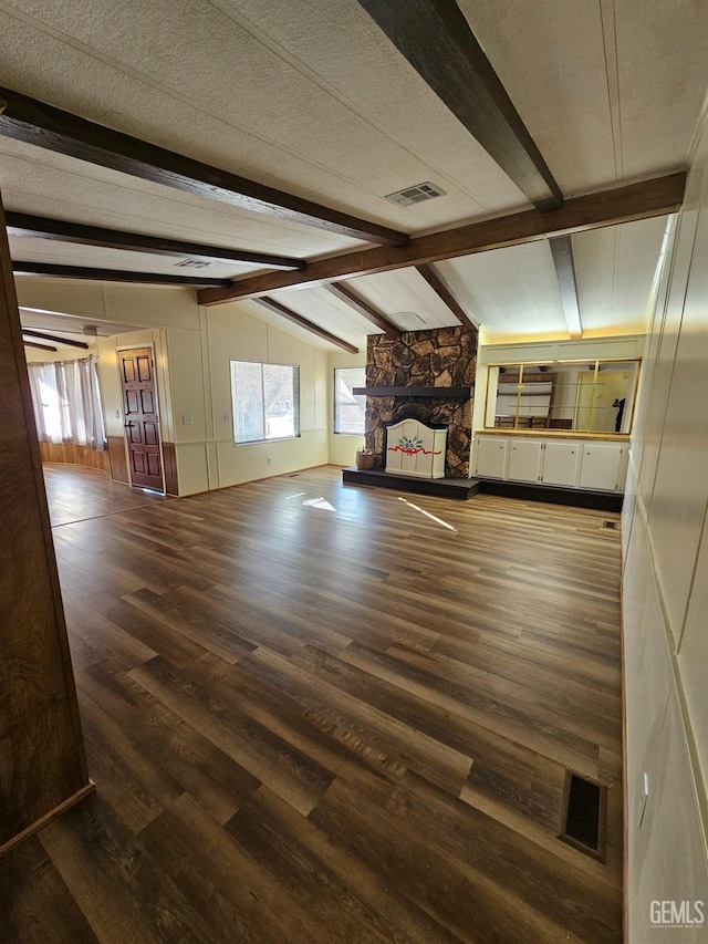 unfurnished living room with a fireplace, lofted ceiling with beams, a textured ceiling, and wood-type flooring