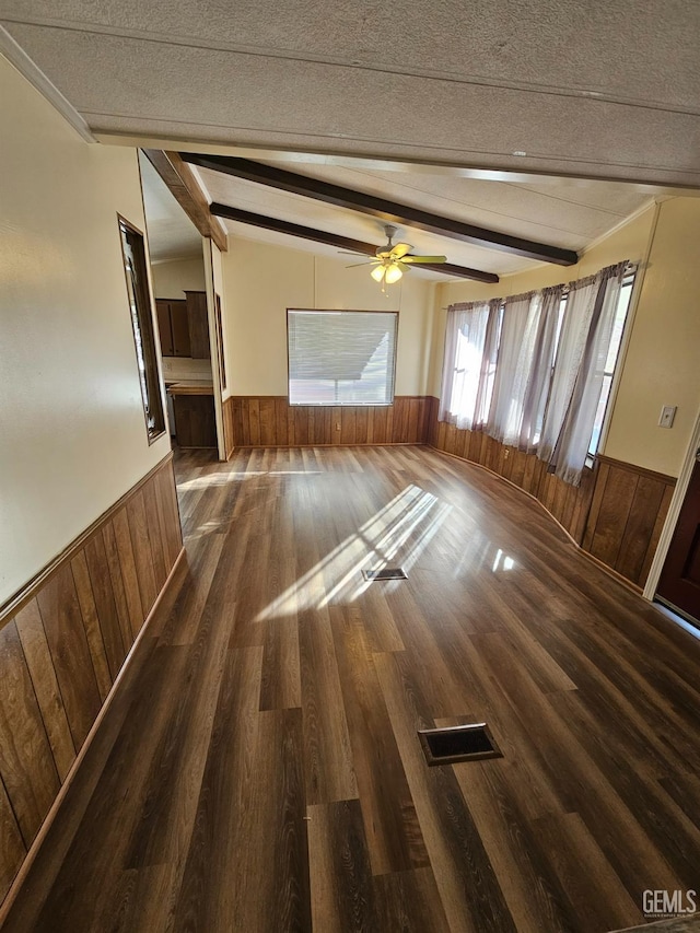 unfurnished living room featuring beamed ceiling, dark hardwood / wood-style floors, and ceiling fan