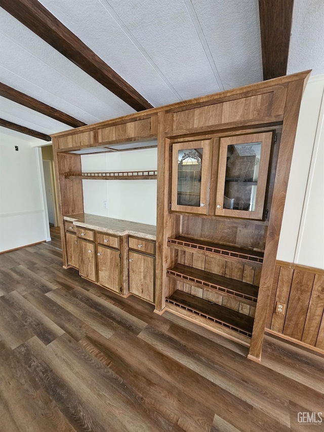 interior space featuring beamed ceiling, a textured ceiling, dark wood-type flooring, and wooden walls