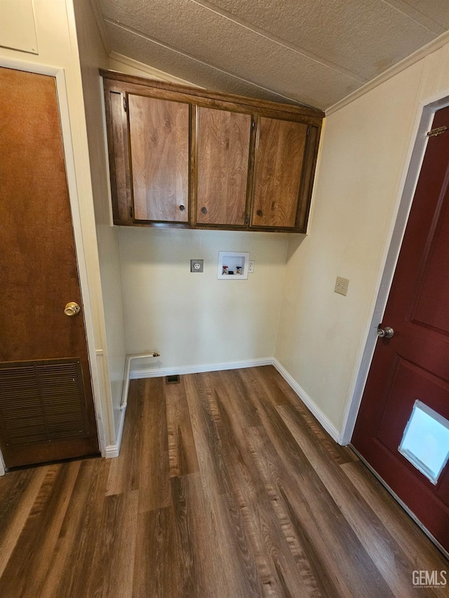 washroom featuring dark wood-type flooring, cabinets, washer hookup, a textured ceiling, and ornamental molding