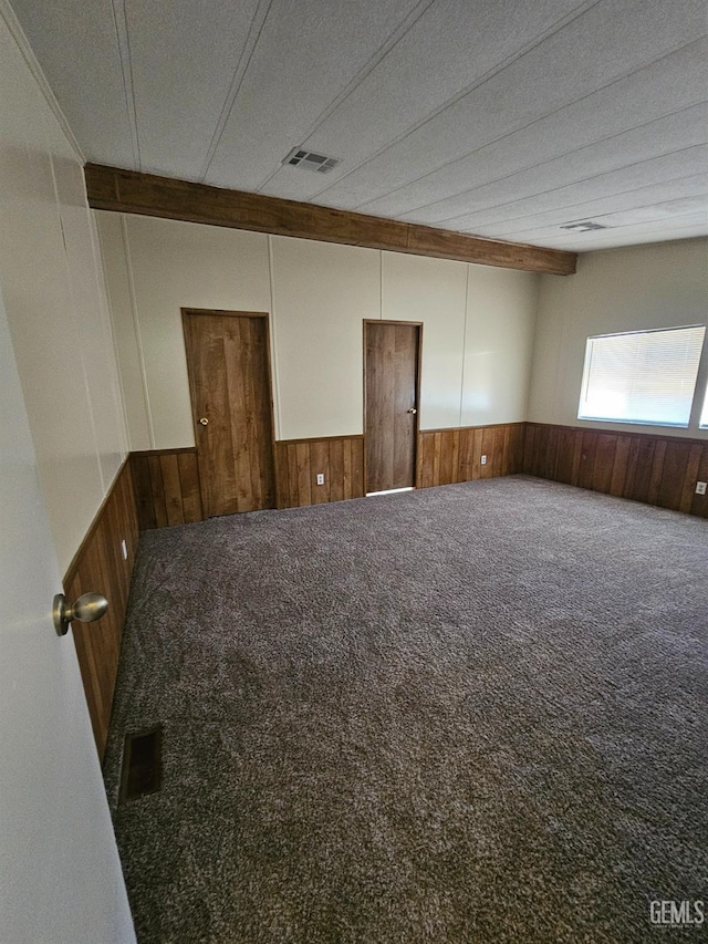 carpeted empty room with wooden walls and a textured ceiling