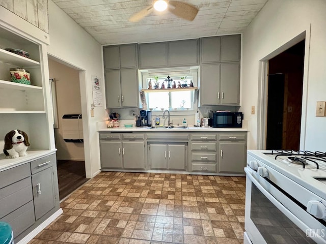 kitchen with a sink, ceiling fan, white gas stove, black microwave, and gray cabinets
