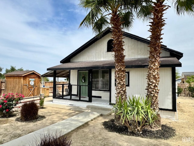 view of front facade with a storage shed, a porch, an outdoor structure, and fence