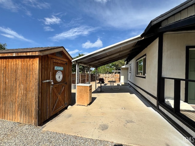 exterior space with a patio area, a storage shed, fence, and an outbuilding