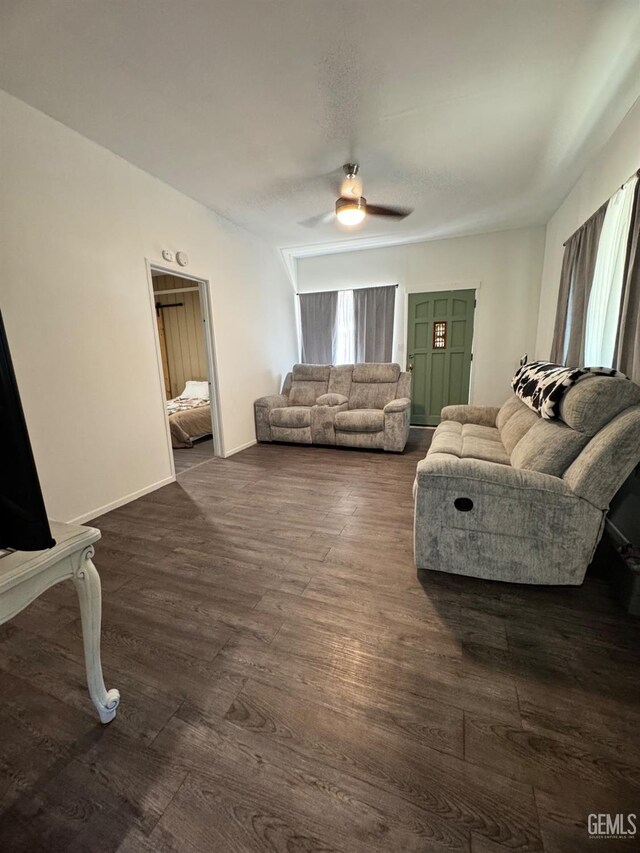 living area featuring baseboards, a ceiling fan, and dark wood finished floors