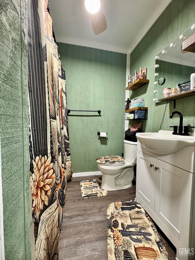 bathroom with vanity, a ceiling fan, toilet, wood finished floors, and baseboards