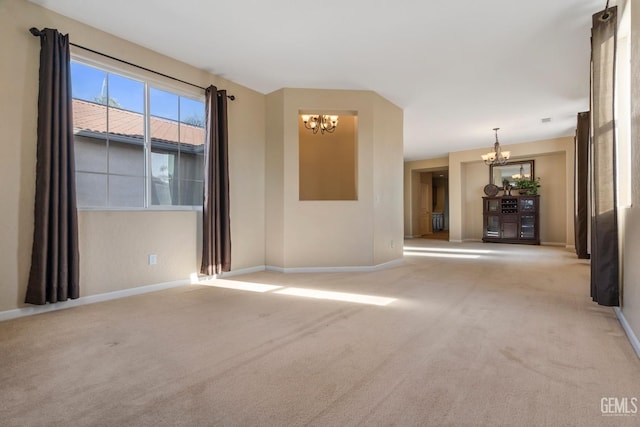 empty room featuring light colored carpet and an inviting chandelier