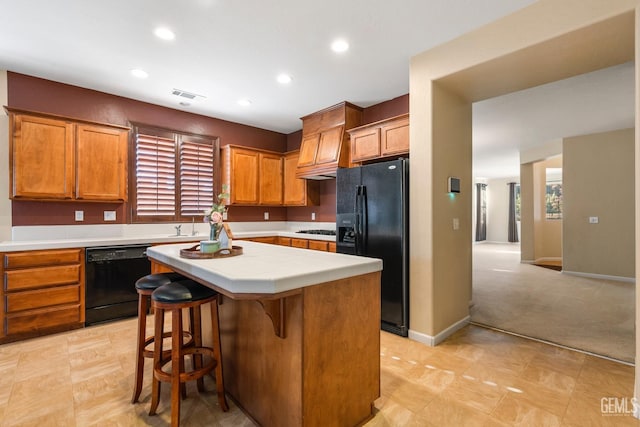 kitchen featuring a breakfast bar, light colored carpet, sink, black appliances, and a kitchen island