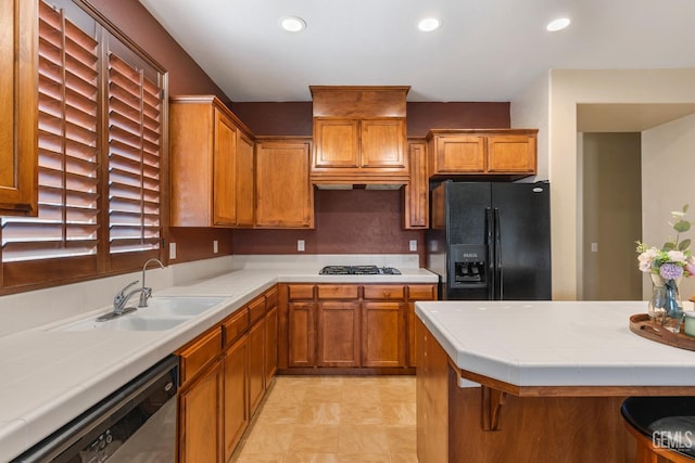 kitchen featuring stainless steel dishwasher, tile counters, black fridge, and sink