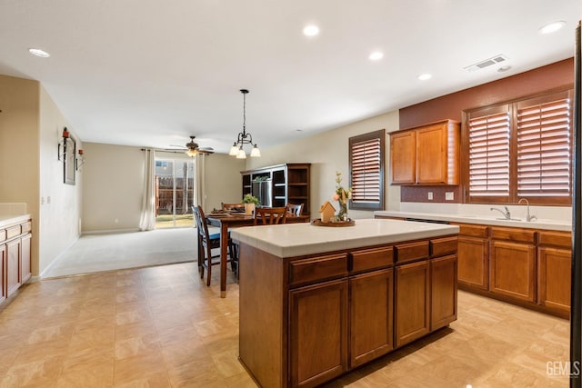 kitchen with decorative light fixtures, a kitchen island, sink, and ceiling fan