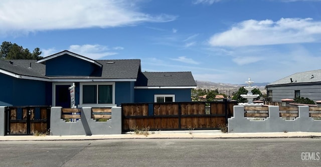 view of front of property featuring a shingled roof, a fenced front yard, and a mountain view